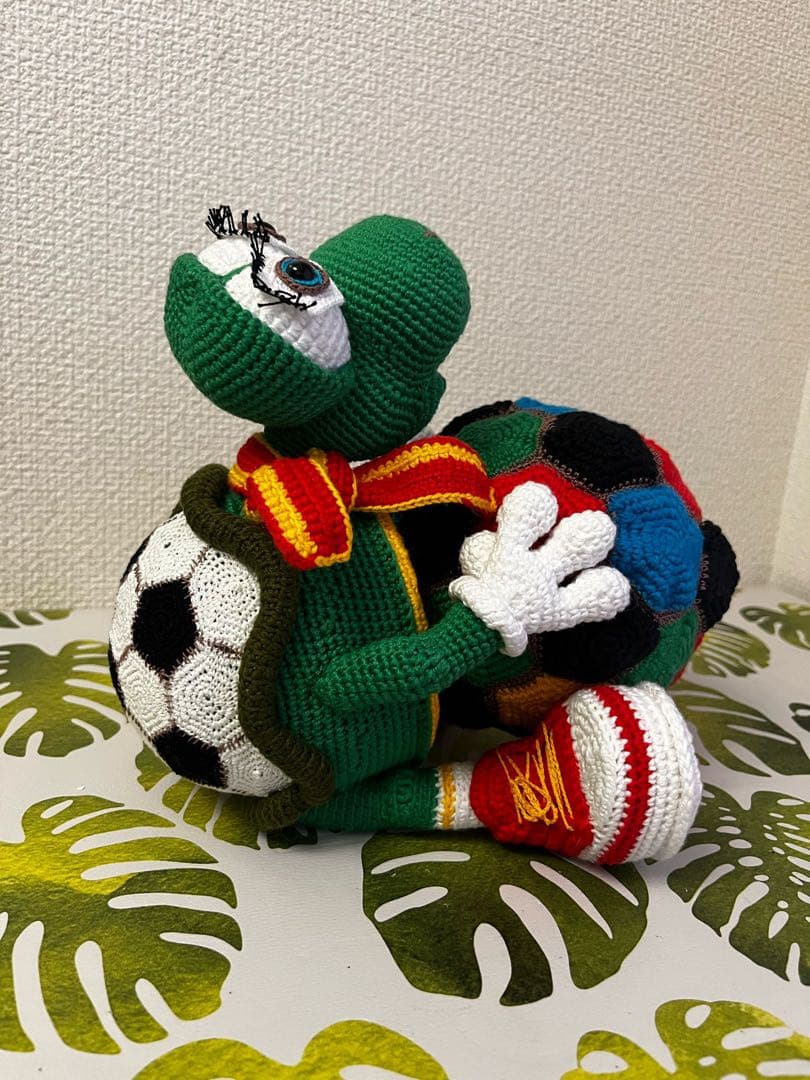 サッカーボールを持つ編み物カメのぬいぐるみ