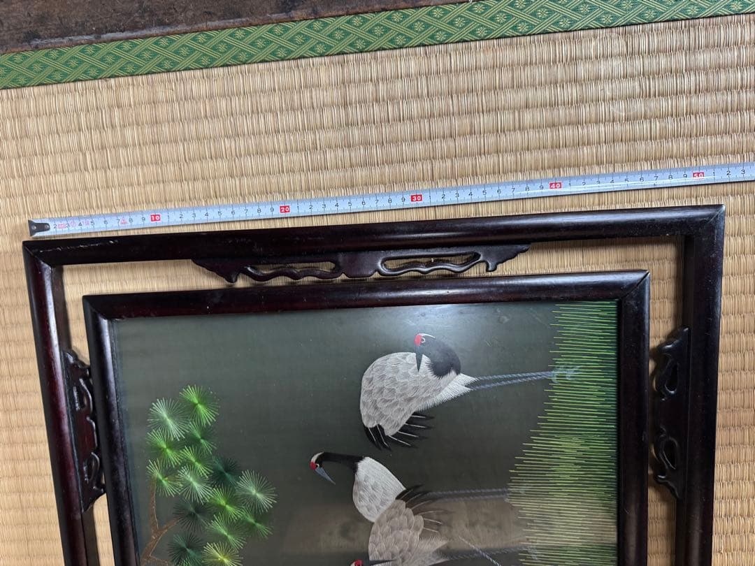 鶴の群れと松の木がデザインされた、額入りの手刺繍のアートワーク